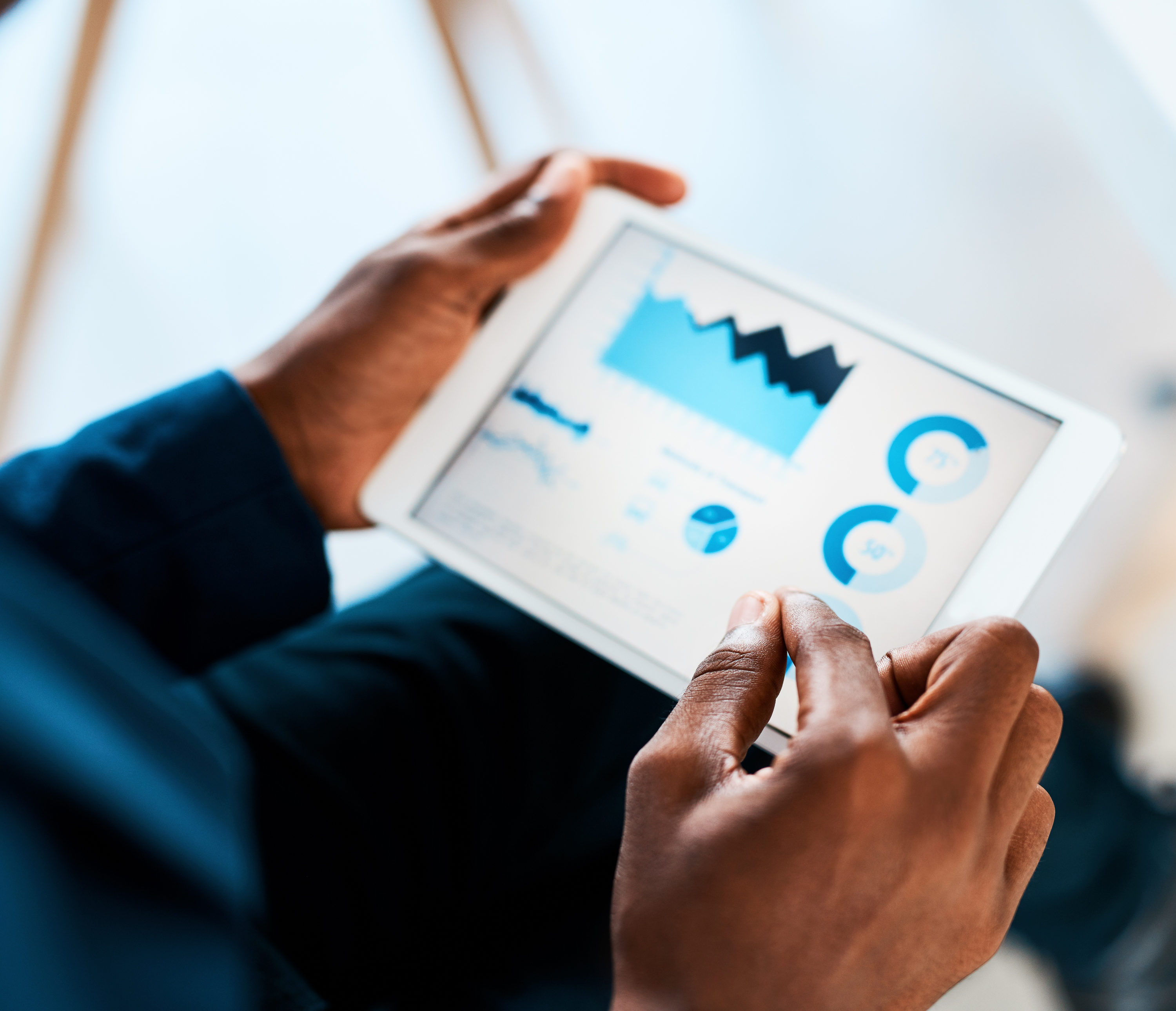 Cropped shot of a businesswoman using a digital tablet with graphs on it in a modern office