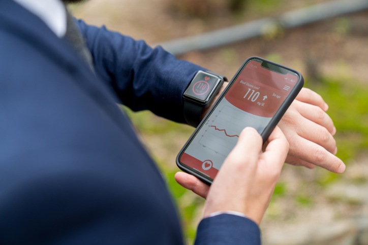 Businessman on the go checking his glucose level using a smartwatch and phone app.